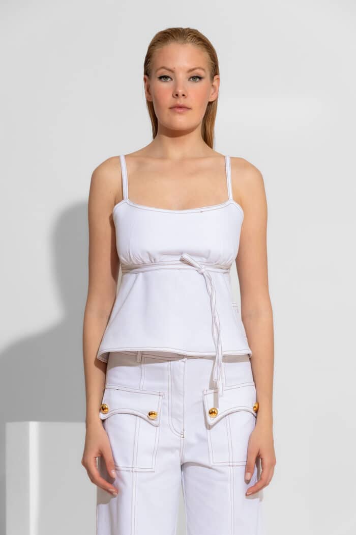 Empire White Denim Camisole Top. A structured white denim top with an empire waist, peplum hem, and adjustable open-back tie. 100% cotton. Made in Greece.